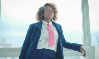 Davina Standing by Window in Her Signature Pink Tie